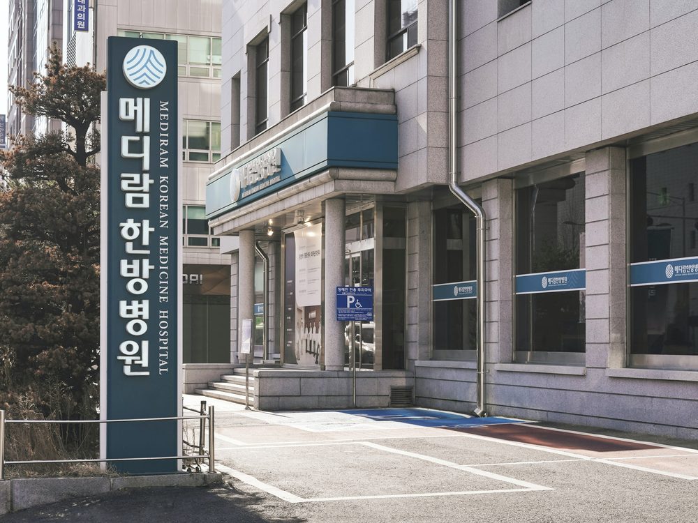 메디람한방병원 세로 간판과 건물 입구, 장애인 주차 구역이 보이는 병원 외관