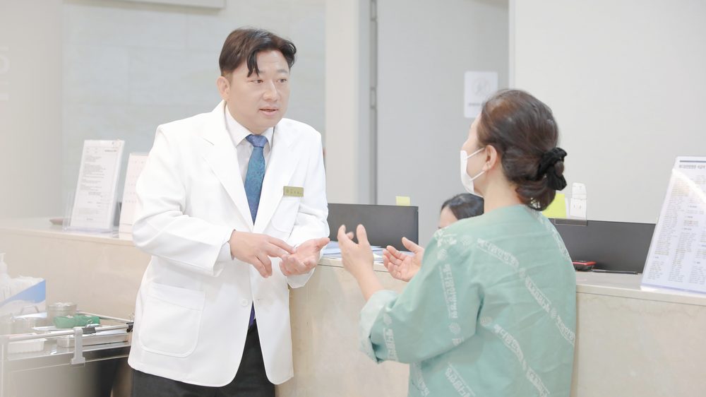 간호사실 데스크 앞에서 원장이 간호사들과 환자별 혈압 기록과 검사 결과를 짚어 가며 이야기하는 모습